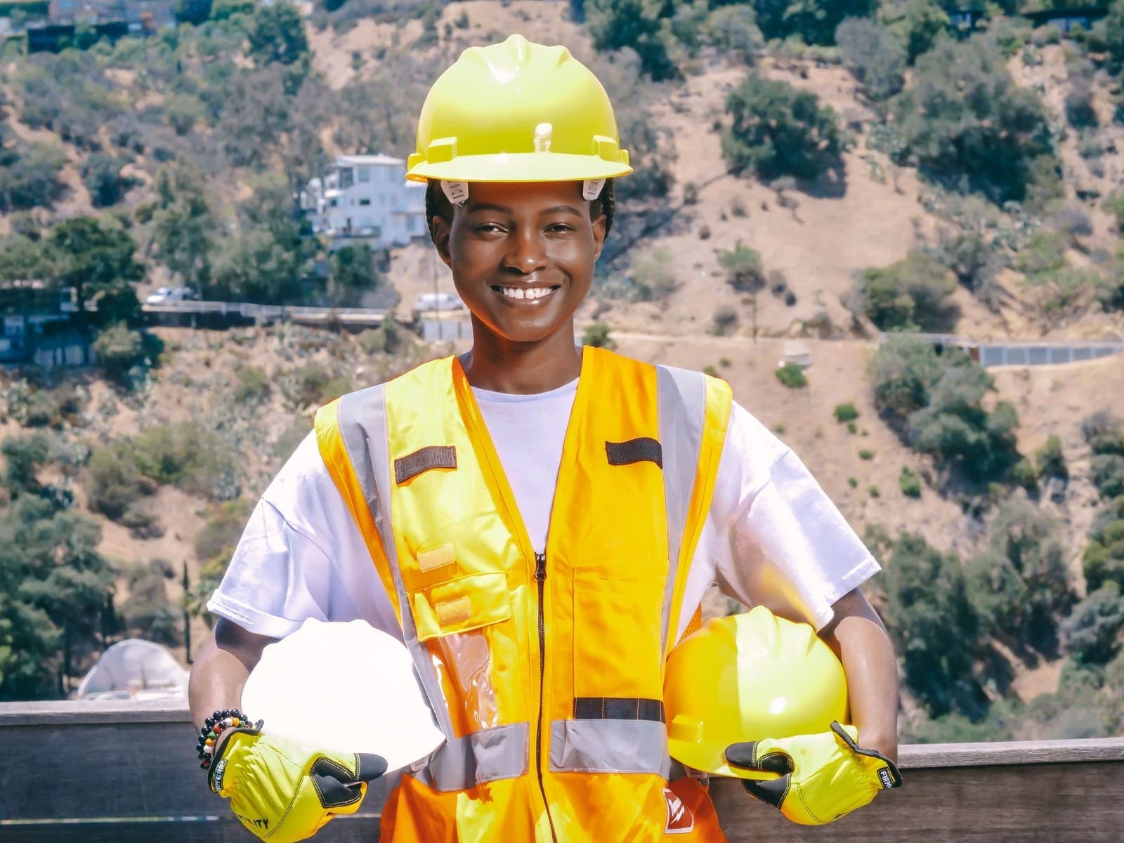 Young construction worker in a hi-vis vest holding a hard hat